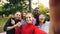 Point of view shot of young woman holding device with camera and taking selfie with friends multi-ethnic group in park