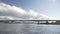 Point of view speedboat floating on river on background of big bridge and city coastline. Cars and trucks pass over the