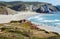 Point view on sunny beach with surfers of Atlantic ocean. Portugal seaside and waves under hot sun