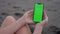 Point of View of woman holds vertical mobile phone two hand touching fingers to centre touch screen. Use green screen