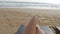 Point of view of young woman lying on sunbed by the sea and tanning. Female legs on chaise-longue relaxing and enjoying