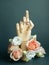 Pointed finger of wooden hand with flowers on dark green background