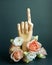 Pointed finger of wooden hand with flowers on dark green background