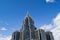 A pointed tower of an office building against a blue sky with clouds. Copy space