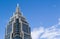 A pointed tower of an office building against a blue sky with clouds. Copy space