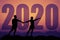 Pointing couple silhouette with big new year 2020 and sunset