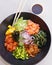 Poke bowl with edamame, salmon, wakame seaweed, mango, radish, cucumber, onion and rice served with sweet soy sauce, japanese food