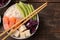 Poke bowl Hawaiian food. plate of rice, salmon, avocado, cabbage and cheese, on a brown wooden table. top view