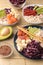 Poke bowl Hawaiian food. a plate of rice, salmon, avocado, cabbage and cheese. next to sesame and fresh avocado on a natural woode