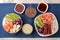 Poke bowl Hawaiian food. a plate with rice, salmon, avocado, cabbage and cheese next to a skunk and soy sauce on a blue napkin on