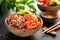 Poke bowl with raw salmon fish, chuka salad and rice in coconut bowls on black background