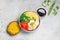 Poke, one of the main dishes of Hawaiian cuisine. Bowl with bulgur, shrimp, chuka salad. On a gray background with sauce