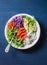 Poke salmon, rice, vegetables buddha power bowl on blue background, top view. Red cabbage, carrots, arugula, rice, smoked salmon f