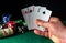 Poker cards with two pairs combination. Close-up of a gambler hand is holding playing cards in casino. Chips on the green table