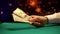 Poker player giving dollar banknotes, casino table background, loosing game