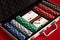 Poker set in metal suitcase. Risky entertainment of gambling. Top view on red background
