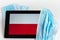 Poland flag covered by surgical protective mask for coronavirus COVID-19 prevention.