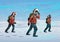 Polar explorers in red jackets marching on the snow in windy weather. Three men walking through the blizzard. Vector