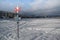 Pole with directions on a frozen, snow-covered lake with cloud-covered mountains and forests in Å re, Sweden