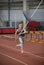 Pole vaulting indoors - young sportive woman running on the runway with a pole in the hands