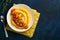 Polenta with butter, pumpkin, garlic, savory and parmesan cheese in white bowl on dark blue concrete background. Traditional Basic