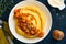 Polenta with butter, pumpkin, garlic, savory and parmesan cheese in white bowl on dark blue concrete background. Traditional Basic