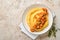 Polenta with butter, pumpkin, garlic, savory and parmesan cheese in white bowl on light concrete background. Traditional Basic