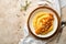 Polenta with butter, pumpkin, garlic, savory and parmesan cheese in white bowl on light concrete background. Traditional Basic Ita