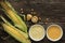 Polenta corn grits and corn flour in a porcelain bowl on a wooden table. Ears of corn and pieces of corn next to bowls. Gluten