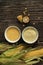 Polenta corn grits and corn flour in a porcelain bowl on a wooden table. Ears of corn and pieces of corn next to bowls. Gluten