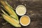 Polenta corn grits and corn flour in a porcelain bowl on a wooden table. Ears of corn and pieces of corn next to bowls. Gluten