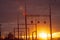 Poles at a power plant at sunset as a background