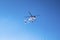 Police helicopter flying above against blue sky on sunny day