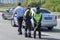 A police officer and a girls two officers near a patrol car in the city with public traffic are guarded. Rear view