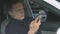 Police officer looking through websites with news on smartphone sitting in car