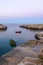 Polignano a Mare (BA): coast of rocks at violet/blu sunset. Some gozzo (fish boats) at anchor