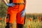 Polish ambulance worker standing in medical orange uniform and blue gloves on hands.