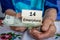 Polish pensioner holds money and wooden blocks with the inscription 14 pension in Polish. Social concept. Additional 13th and