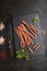 Polish smoked sausage kabanos on a slate cutting board on black concrete background. Top view, close up