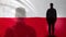 Polish soldier silhouette standing against national flag, proud army sergeant
