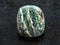 polished chrysotile gemstone on dark background