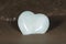 Polished cream white carved Onyx Heart on wet sand on the beach at sunrise in front of the lake. Love, Romance and Friendship