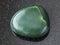 polished green nephrite gemstone on dark