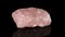 Polished mineral stone rose quartz rotates in a circle on a black background