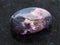 polished Rhodonite gemstone on dark background