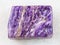 polished slab of charoite gemstone on white marble