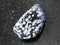 Polished snowflake obsidian gem stone on dark