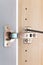 Polished stainless door hinge on a opened cabinet door for interior design. Heavy-duty hinges are designed to provide support and