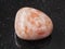 polished sunstone (heliolite) gem stone on dark