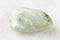 polished vesuvianite gemstone on white marble